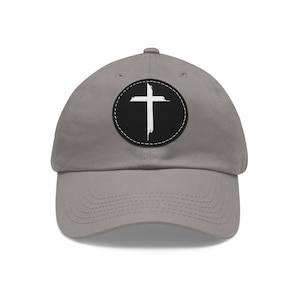 Peut inclure: Une casquette de baseball grise avec un motif de croix noir et blanc dans un cercle sur le devant.