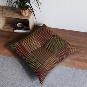 May include: A large floor pillow with a patchwork design featuring a variety of plaid patterns in shades of red, orange, green, and brown.
