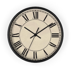 Könnte beinhalten: Eine schwarze Uhr mit römischen Ziffern auf einem cremefarbenen Zifferblatt. Die Zeiger der Uhr sind schwarz.