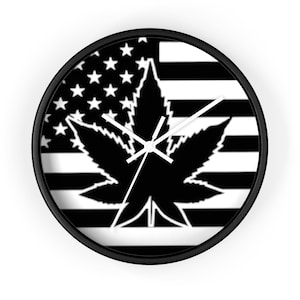 Op de afbeelding: Zwarte en witte wandklok met een marihuanabladontwerp dat is gelegd over een Amerikaans vlagpatroon.