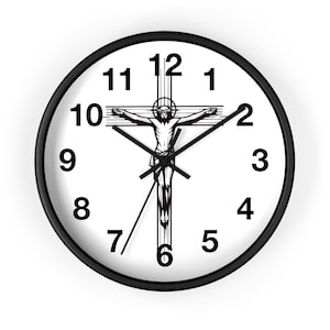 May include: A white clock face with black Roman numeral hour markers and black hands. The clock face features a black and white image of a crucifix with a figure of Jesus Christ.