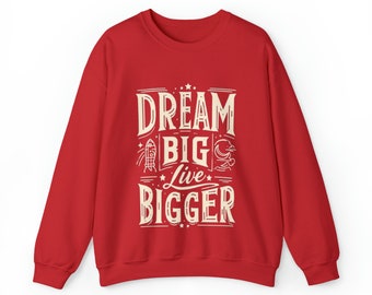 Könnte beinhalten: Roter Pullover mit einem weißen Grafikdruck, der "Dream Big Live Bigger" mit Sternen und anderen kleinen Designelementen sagt.