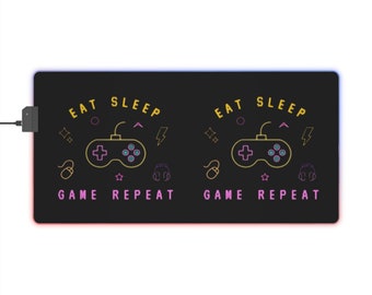 May include: Black gaming mouse pad with a yellow and purple outline of a video game controller and the text "Eat Sleep Game Repeat" on either side.