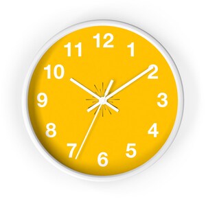 Puede incluir: Un reloj redondo amarillo con números y manecillas blancas. La esfera del reloj tiene un borde blanco y los números del 1 al 12 se muestran alrededor del borde.