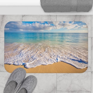 Könnte beinhalten: Eine Strand-Badematte mit einem Foto eines Sandstrandes mit blauem Wasser und weißen, schaumigen Wellen.