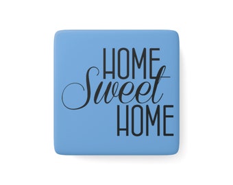 Könnte beinhalten: Ein quadratischer, hellblauer Dekorationsartikel mit den Worten "HOME Sweet HOME" in schwarzer Schrift und Blockbuchstaben. Der Artikel hat eine glatte Oberfläche und ist einfarbig.