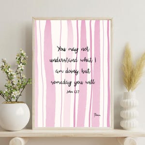 May include: Framed art print with a pink and white striped background. The print features the quote "You may not understand what I am doing, but someday you will" from John 13:7. The artwork is displayed on a wooden shelf.