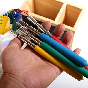 May include: Set of five telescopic reachers with different coloured handles. The handles are red, blue, green, yellow, and a combination of yellow and green. The reachers have a metal shaft and a variety of attachments, including a rake, a claw, and a hook.