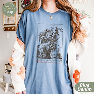 May include: A blue denim t-shirt with a vintage illustration of a knight on horseback. The text "I want to battle for the right" is printed below the illustration.