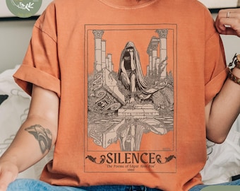 May include: Yam-colored t-shirt featuring a vintage illustration of a cloaked figure in a ruined landscape. The artwork, framed in a rectangle, includes the word "SILENCE" and the text "The Poems of Edgar Allan Poe 1906".