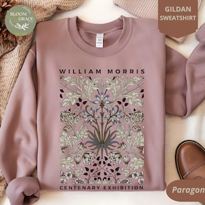 Puede incluir: Una sudadera Gildan rosa polvorienta con un diseño floral y el texto "William Morris Centenary Exhibition".