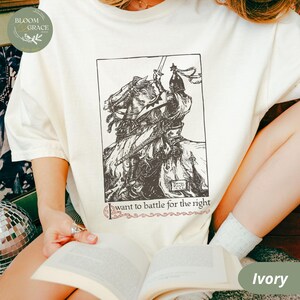 May include: A white t-shirt with a black and white illustration of a knight on horseback. The text "I want to battle for the right" is printed below the illustration. The shirt is available in the color ivory.