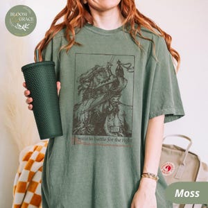 A vintage-inspired medieval knight t-shirt featuring an intricate historical illustration of a warrior in battle, printed on a moss-green Comfort Colors tee.