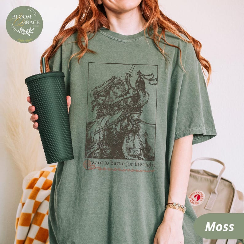 A vintage-inspired medieval knight t-shirt featuring an intricate historical illustration of a warrior in battle, printed on a moss-green Comfort Colors tee.