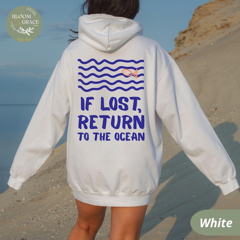 May include: White hoodie with blue text that reads "IF LOST, RETURN TO THE OCEAN." The back of the hoodie features a blue wave design with a small orange fish. The hoodie is a comfortable, casual style.