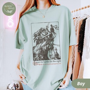 May include: A light blue t-shirt with a black and white illustration of a knight on horseback. The text "I want to battle for the right" is printed below the illustration.