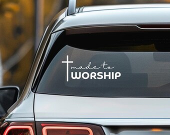 May include: A white vinyl decal with a cross and the text "made to worship" on a silver car.