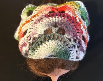 May include: A colorful, handmade crochet hat. The hat features a mix of vibrant colors including red, green, purple, and white. The open weave design adds a unique texture. This hat is a stylish accessory.
