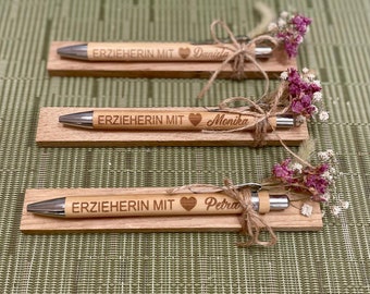 May include: Three wooden pen holders with engraved pens and dried flowers. Each pen holder has the text "ERZIEHERIN MIT" followed by a heart and a name: "Daniela", "Monika", and "Petra".