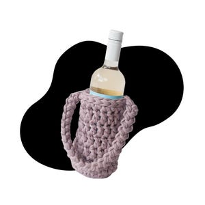 May include: A glass wine bottle with a white screw cap is held inside a dusty mauve, thick-yarn crochet bottle carrier. The carrier features a cylindrical body with a textured, chunky knit pattern and two sturdy, braided handles on the sides.