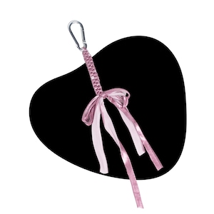 May include: A light pink keychain featuring a braided cord attached to a silver metal carabiner. The cord is adorned with a decorative bow made from matching pink satin ribbon, with three long ribbon tails hanging down from the center knot.