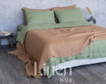 Può includere: Un copripiumino in lino marrone con federe in lino verde e un lenzuolo in lino verde su un letto con una testata bianca. Il letto si trova in una stanza con una parete in cemento grigio e un pavimento in legno.