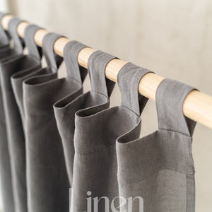 Puede incluir: Cortinas de lino grises con una barra de madera y el texto "Linen HUE" impreso en la tela.