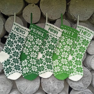 May include: Five green and white knitted Christmas stockings with names embroidered on them: Hero, Pearl, Aria, Matt, and Theo.