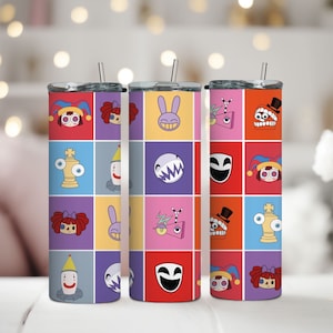 Puede incluir: Tres vasos de acero inoxidable con diseños cuadrados coloridos que presentan personajes de dibujos animados. Cada vaso tiene un conjunto diferente de personajes, que incluyen un bufón, un conejito, un fantasma, un payaso y un robot.