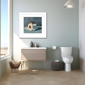 May include: A framed artwork depicts a turtle atop a roll of toilet paper. The artwork is in a white frame and hangs above a bathroom vanity. The bathroom has a toilet, a small stool, and a window with a view of the beach.