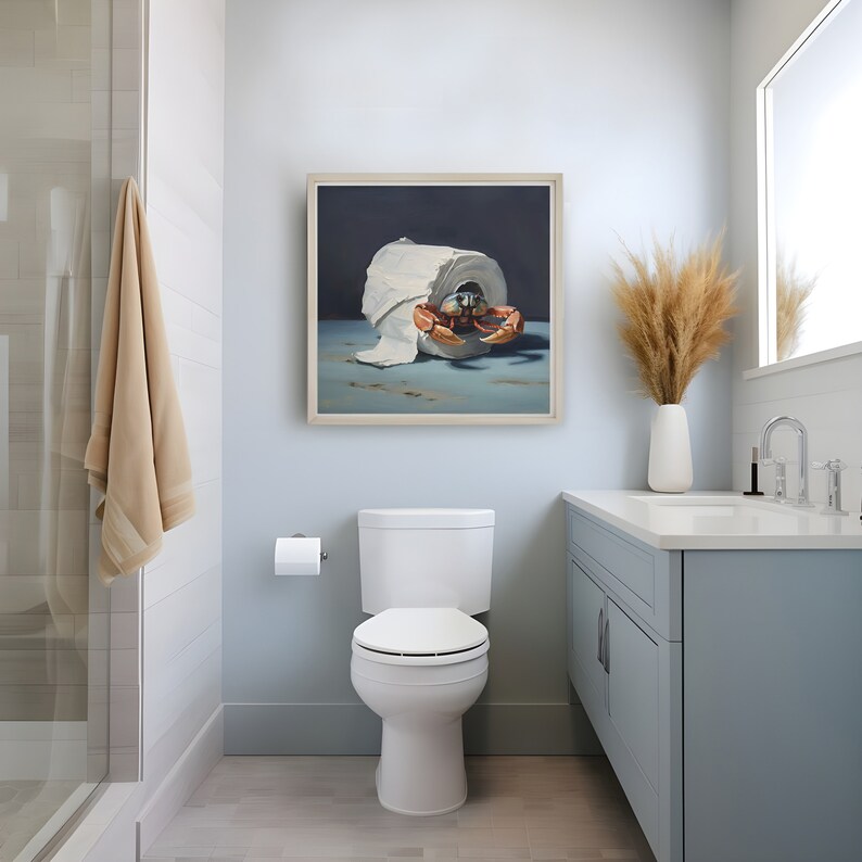 A coastal themed bathroom with a painting on the wall. The painting is of a crab crawling out of a roll of toilet paper against a dark background.