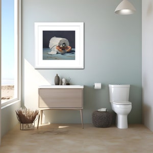 A coastal-themed bathroom with a painting on the wall. The painting is of a crab crawling out of a roll of toilet paper against a dark background.