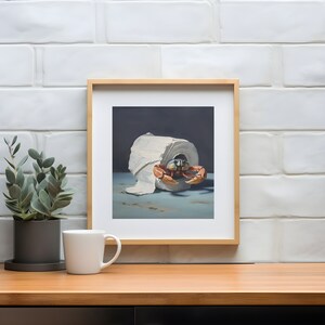 A framed painting of a crab crawling out of a roll of toilet paper against a dark background. A coffee mug and a plant are on a table in front of the painting.