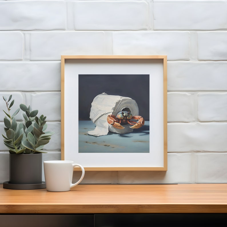 A framed painting of a crab crawling out of a roll of toilet paper against a dark background. A coffee mug and a plant are on a table in front of the painting.