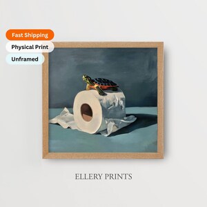 May include: A framed print featuring a turtle atop a roll of toilet paper. The artwork has a blue and green color palette. The text "ELLERY PRINTS" is at the bottom of the frame.