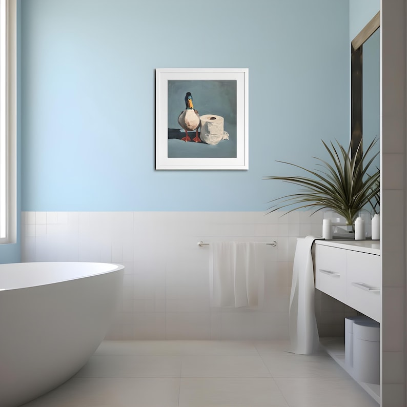 May include: A framed artwork depicts a mallard duck standing next to a roll of toilet paper. The duck has a green head, white neck ring, and brown body. The artwork is set against a blue background, creating a humorous bathroom-themed piece.