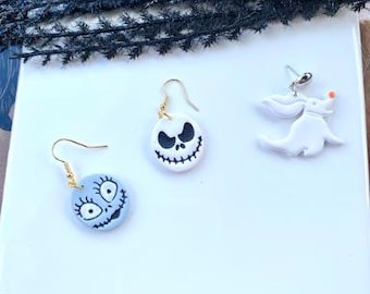 May include: Three pairs of polymer clay earrings featuring characters from the Nightmare Before Christmas. The earrings are white and gray with black details. The characters are Jack Skellington, Sally, and Zero the ghost dog.