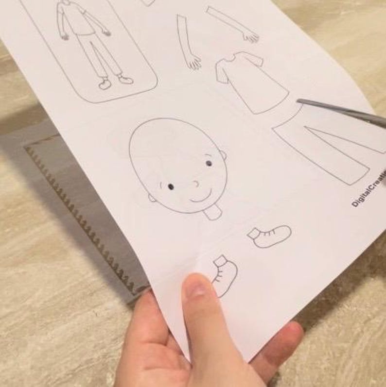 Puede incluir: Una actividad de manualidades de papel imprimible con un contorno en blanco y negro de una persona con varias partes del cuerpo para cortar y ensamblar. Las partes incluyen una cabeza, brazos, piernas, torso y zapatos.