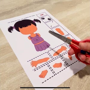 Puede incluir: Una actividad de mu&ntilde;eca de papel imprimible con una ni&ntilde;a de dibujos animados con cabello morado y un vestido morado. La mu&ntilde;eca se recorta y las partes se separan para que los ni&ntilde;os puedan ensamblarla. Las instrucciones dicen "Corta a lo largo de las l&iacute;neas y completa la mu&ntilde;eca."