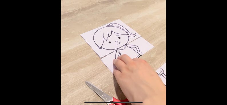 Puede incluir: Un dibujo en blanco y negro de una ni&ntilde;a con una coleta, que lleva una camisa, en una hoja de papel blanca. Una mano sostiene el papel y un par de tijeras rojas est&aacute;n en el fondo.