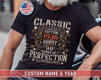 Può includere: T-shirt nero con un design vintage. La maglietta presenta il testo "CLASSIC LIMITED EDITION 1936 BOBBY 90 YEARS OF PERFECTION ALL ORIGINAL PARTS". La maglietta ha anche una sezione "CUSTOM NAME & YEAR".