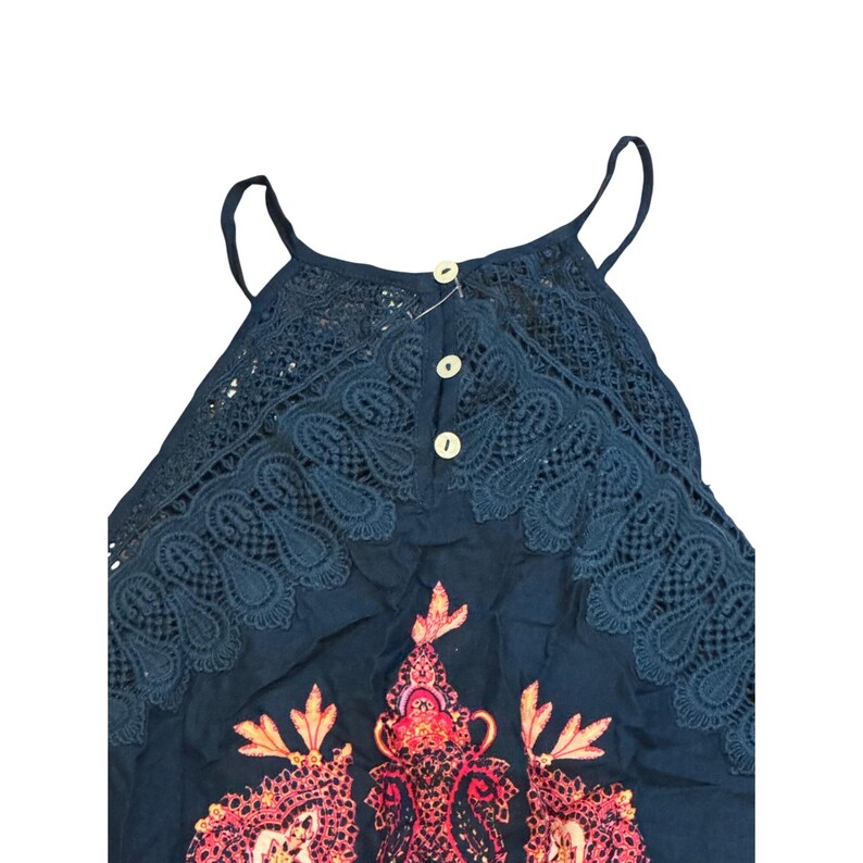May include: A navy blue tank top with a decorative paisley pattern in shades of pink and orange. The top features a lace yoke with three small buttons and thin spaghetti straps.
