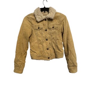 May include: A tan corduroy jacket with a cream-colored faux fur collar. The jacket has a button-up front, two chest pockets, and two side pockets. The jacket is hanging on a black hanger.