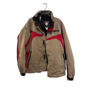Puede incluir: Chaqueta de invierno beige y roja con la marca "DESCENTE" en el pecho y el cuello. La chaqueta tiene cuello y puños negros, con detalles rojos en los hombros y los laterales. Colgada de una percha negra.