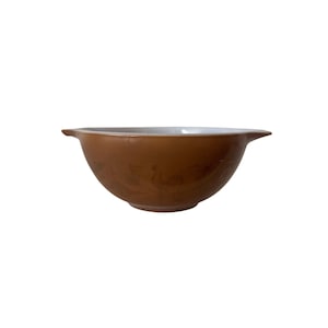 Puede incluir: Un tazón mezclador de cerámica marrón con interior blanco y diseño floral. El tazón tiene dos asas a los lados.