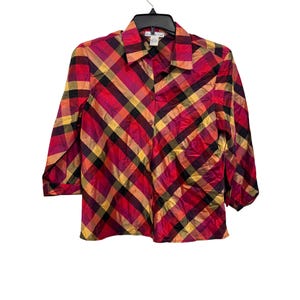 May include: A button-down shirt featuring a vibrant diagonal plaid pattern in shades of red, orange, yellow, and black. The shirt has a classic collar, long sleeves with cuffs, and a front button placket. The fabric has a subtle sheen throughout.