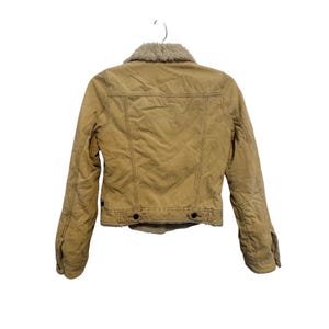 May include: Tan corduroy jacket with a faux fur collar. The jacket has a button-up front, two chest pockets, and two side pockets. The jacket is hanging on a white background.