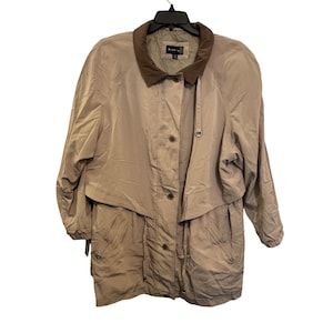 May include: Tan-colored trench coat with a brown collar and button closure. The coat has a classic design with a mid-length cut and a relaxed fit. The coat is hanging on a black hanger.