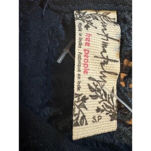 May include: Close-up of a navy blue garment with a Free People label attached. The label is cream-colored with the brand name in a stylized font and the text "Made in India, Fabriqu&eacute; en Inde". The size is S.P.