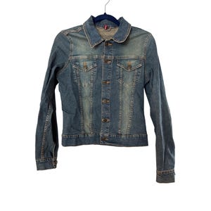 May include: A blue denim jacket with a button closure and two front pockets. The jacket has a faded look and is made of a soft, comfortable material.